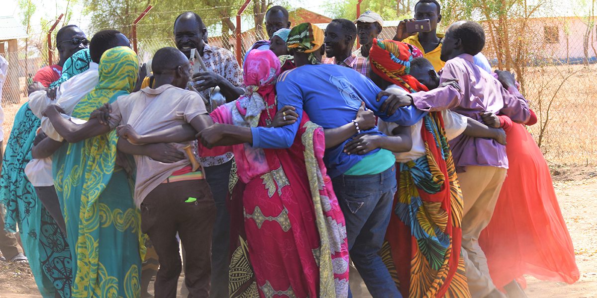 A group of adults dance, sing, and stomp their feet in a circle as they prepare for an International Women's Day celebration in Maban, South Sudan.