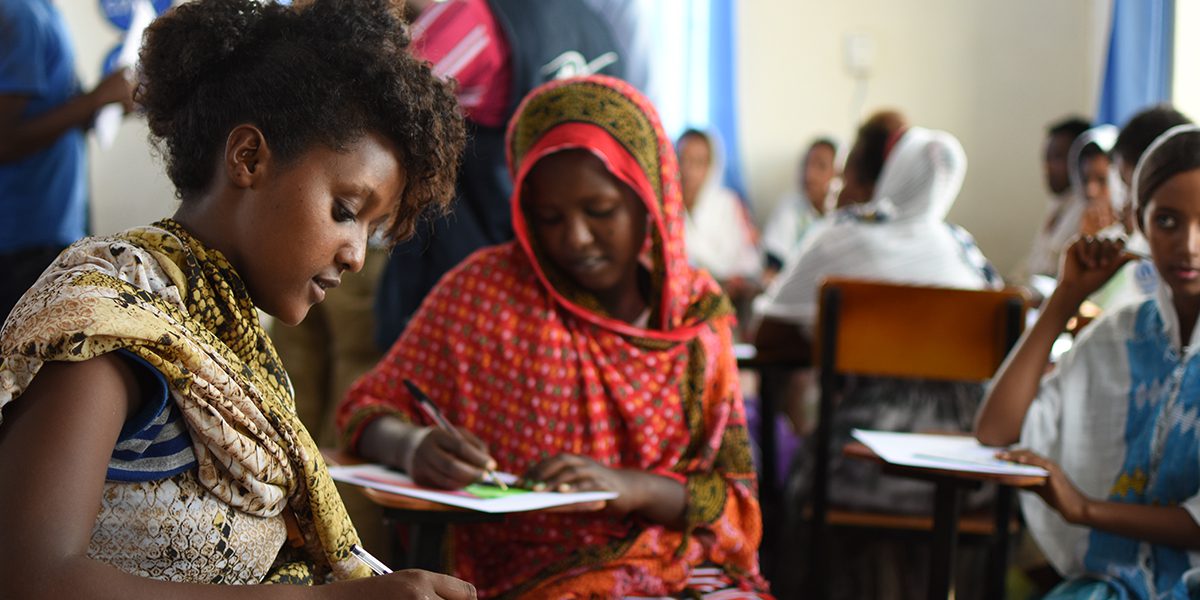 Students writing postcards back to class in London who sent cards to Any Refugee project.