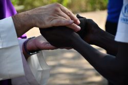  The Charge’ de’ Affaires of the Apostolic Nunciature of Vatican in Juba, H.E. Ionut Paul Strejac, holding hands of a refugee in Maban during a mass in December 2022.